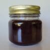 A jar of chocolate pudding with gold lid.